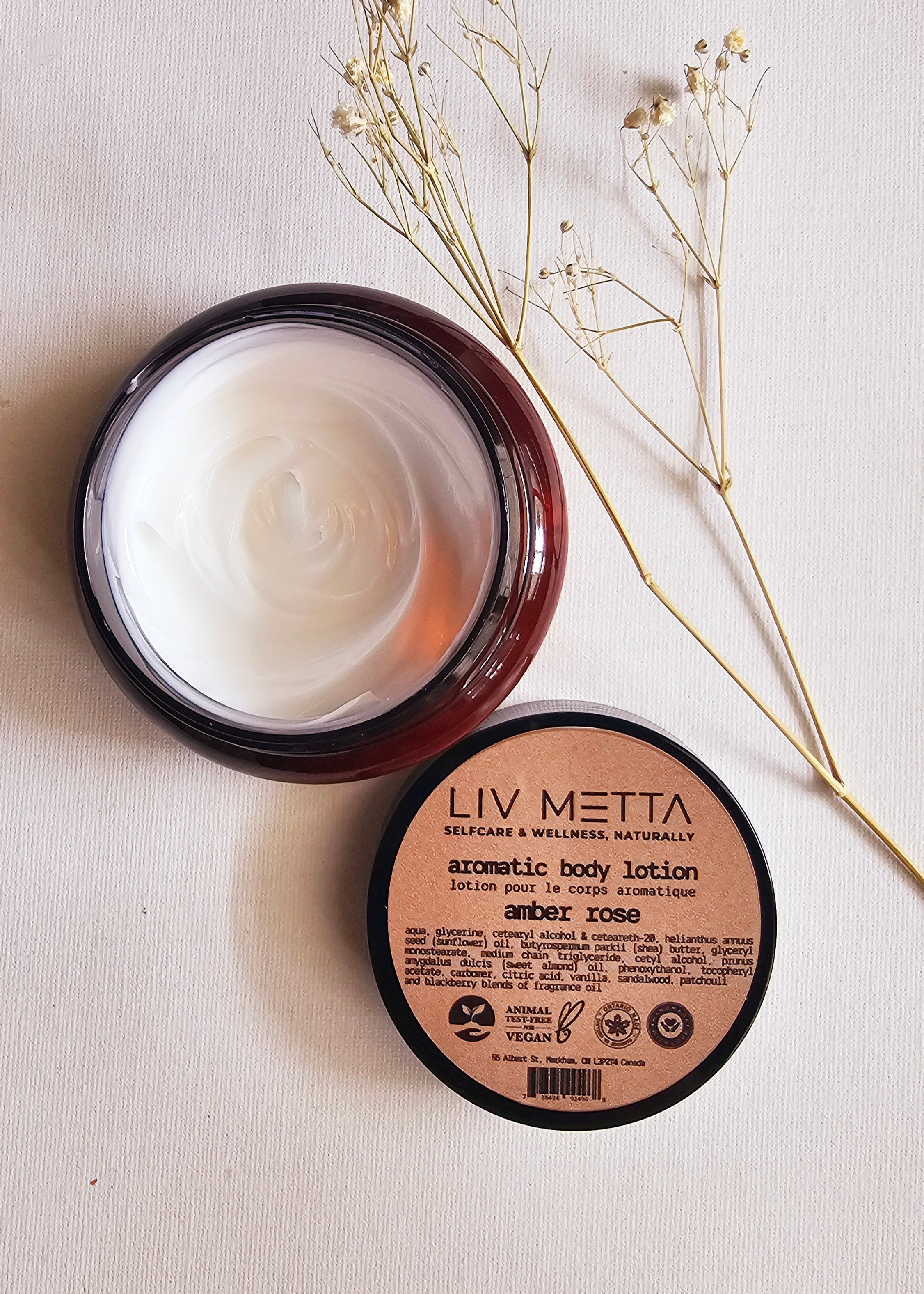 Amber jar with cream and cover on the bottom, dry flowers on the side