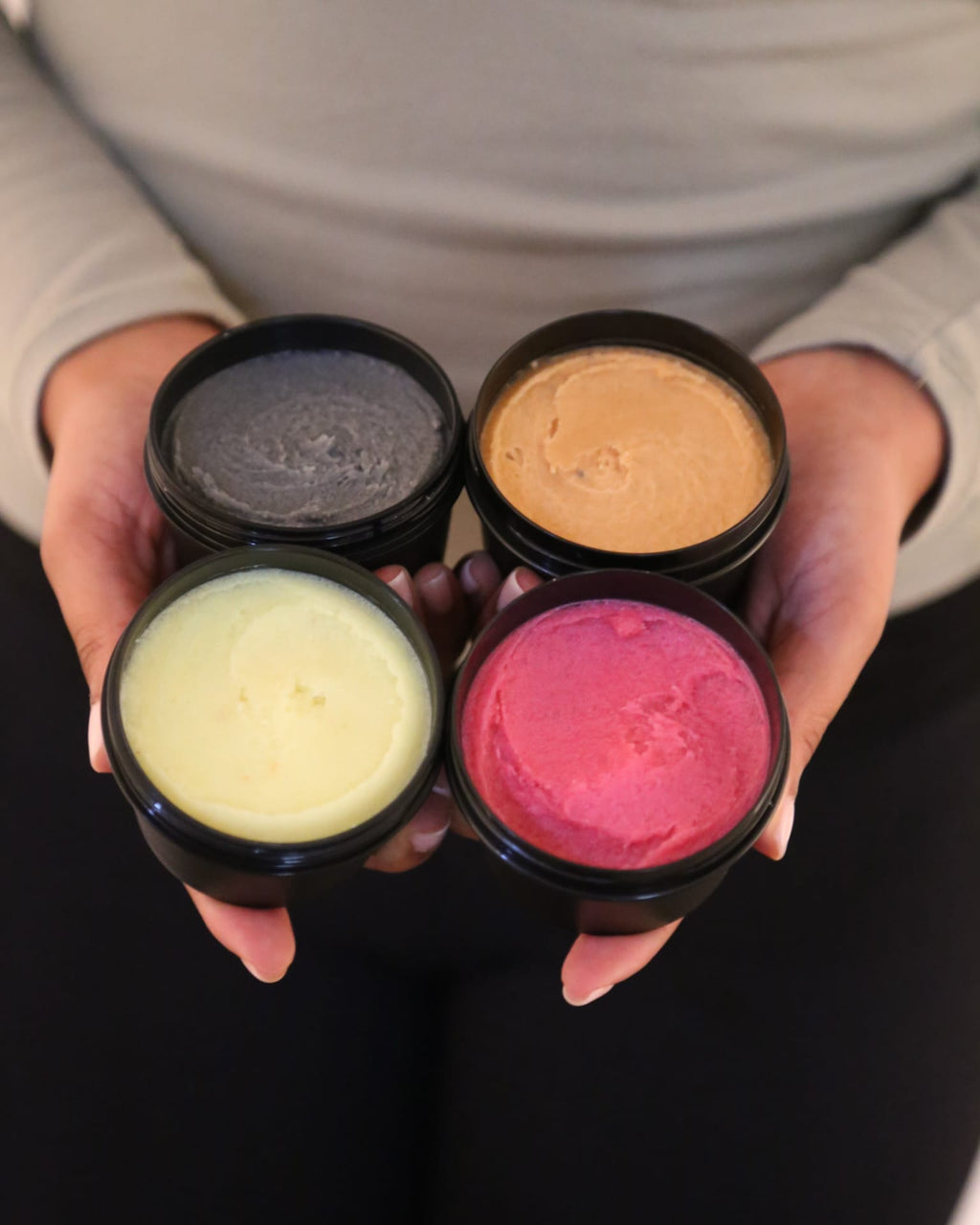 Four small containers with different colored contents held by a person.