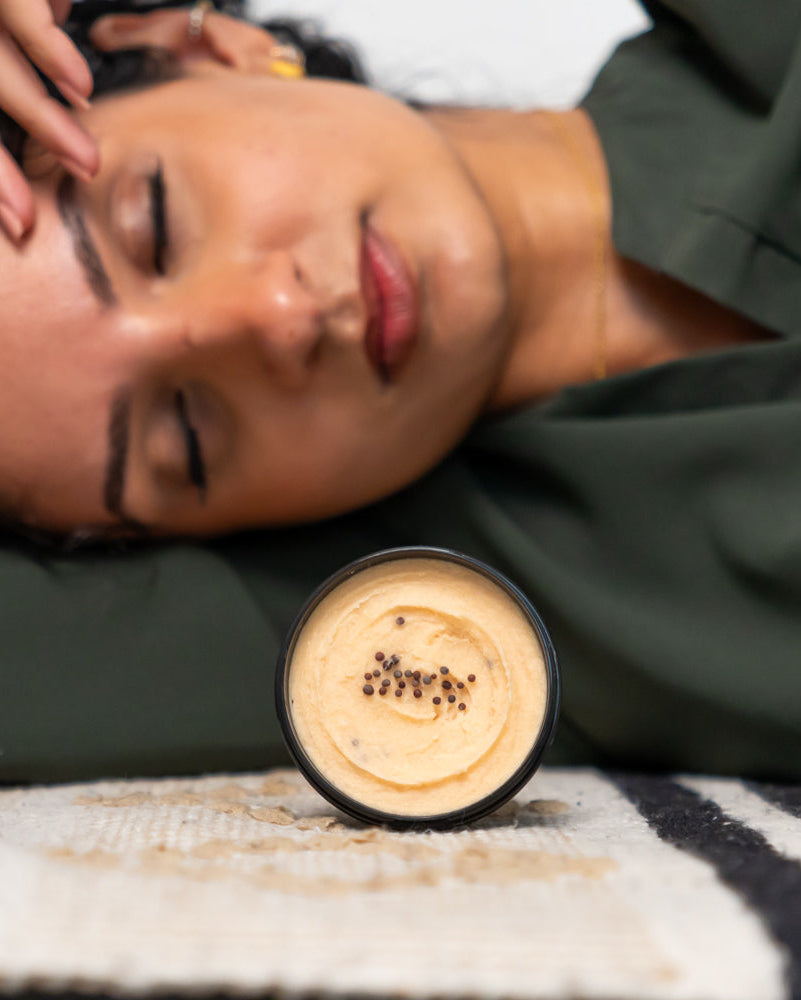 Woman lying down with a jar of cream on a textured surface