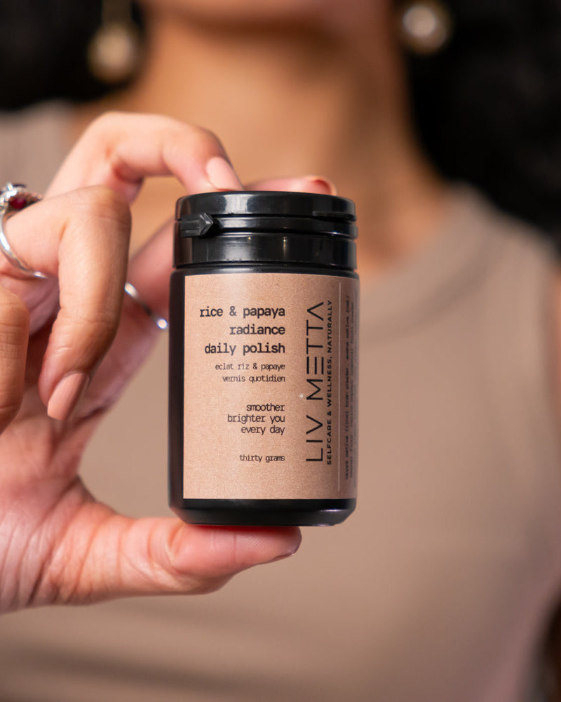 Person holding a black container with 'LIV METTA' branding against a neutral background