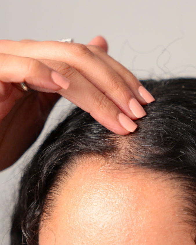 Woman applying oil in her hair