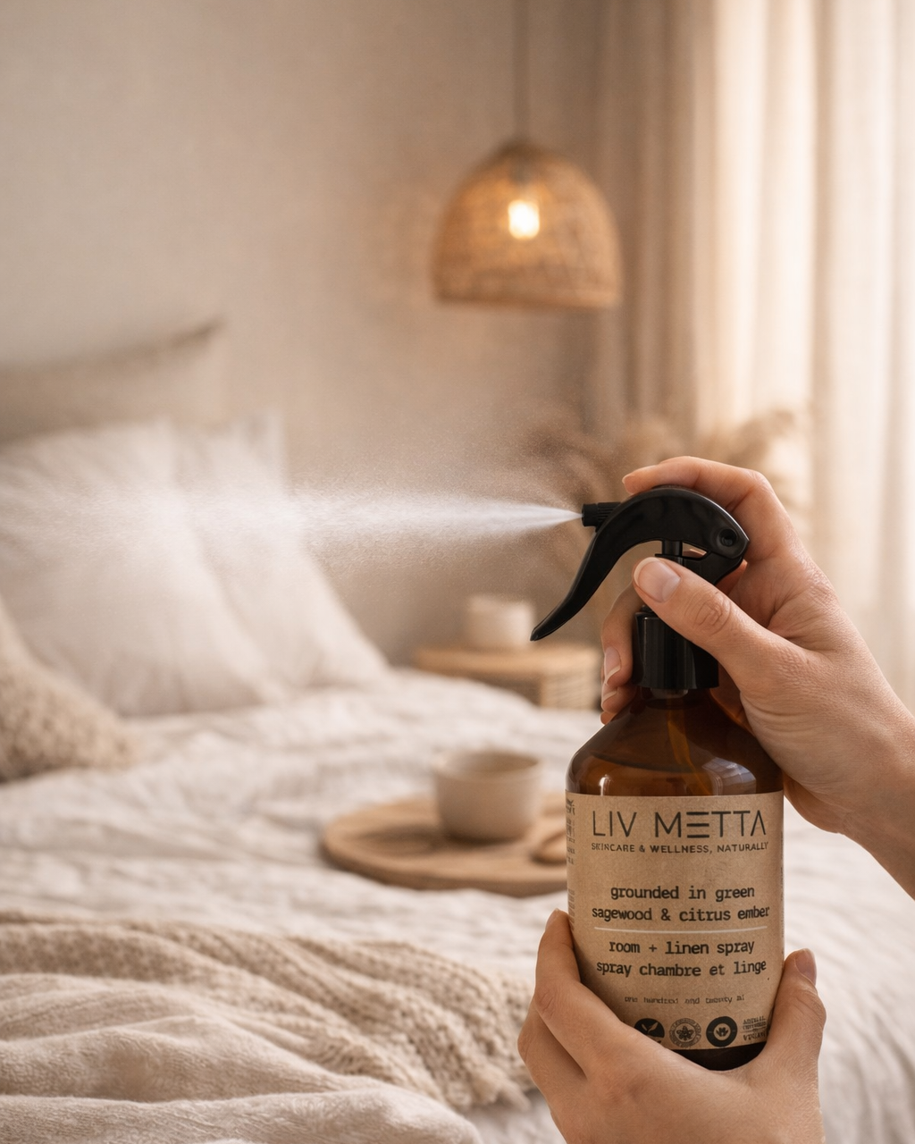 Person holding a 'LIV METTA' spray bottle in a cozy bedroom setting.
