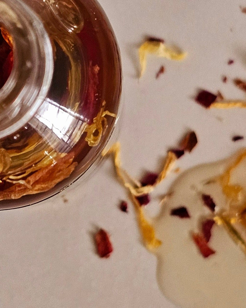 Silver cup with dried flowers and petals on a white surface