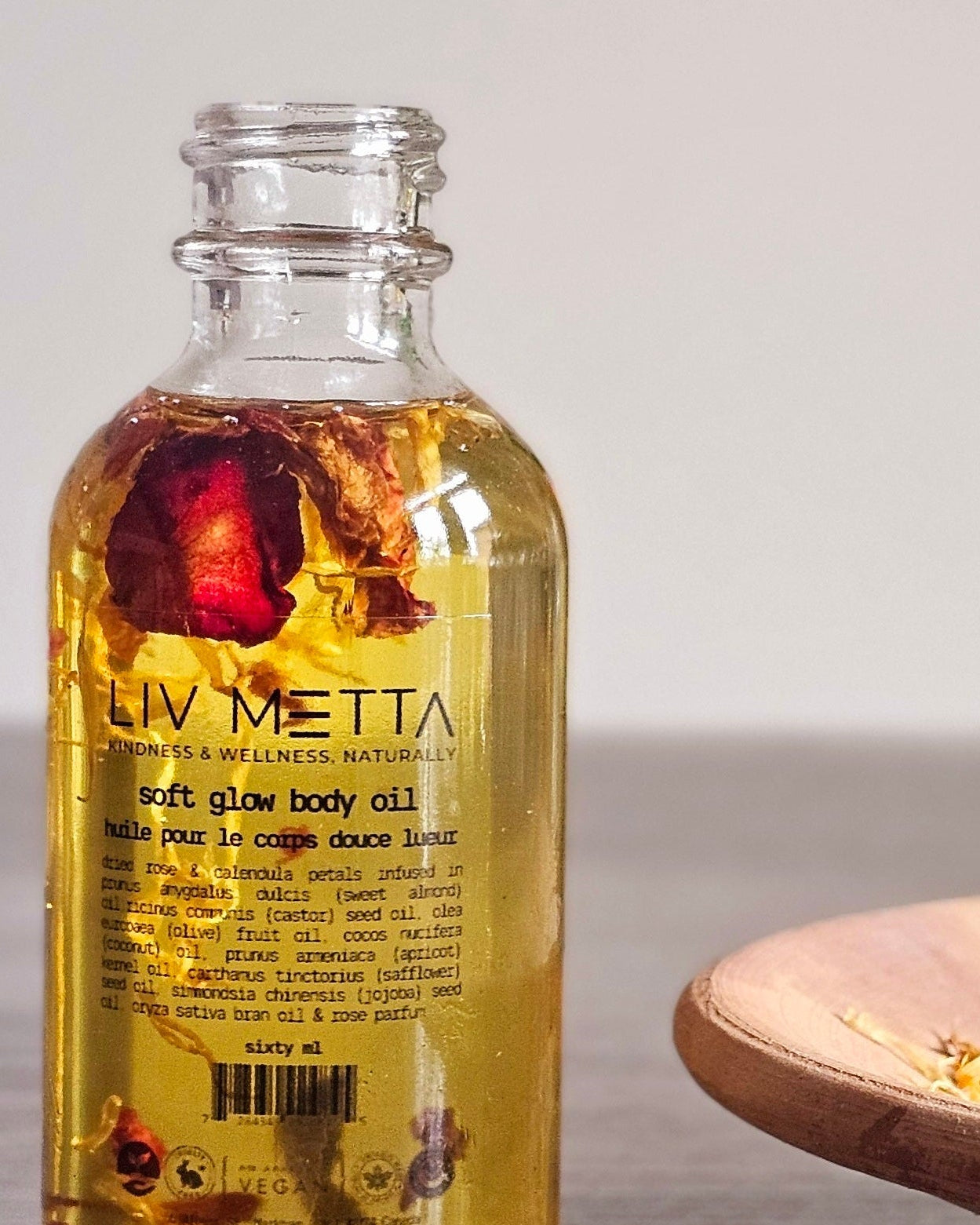Bottle of Liv Metta soft glow body oil with a blurred background