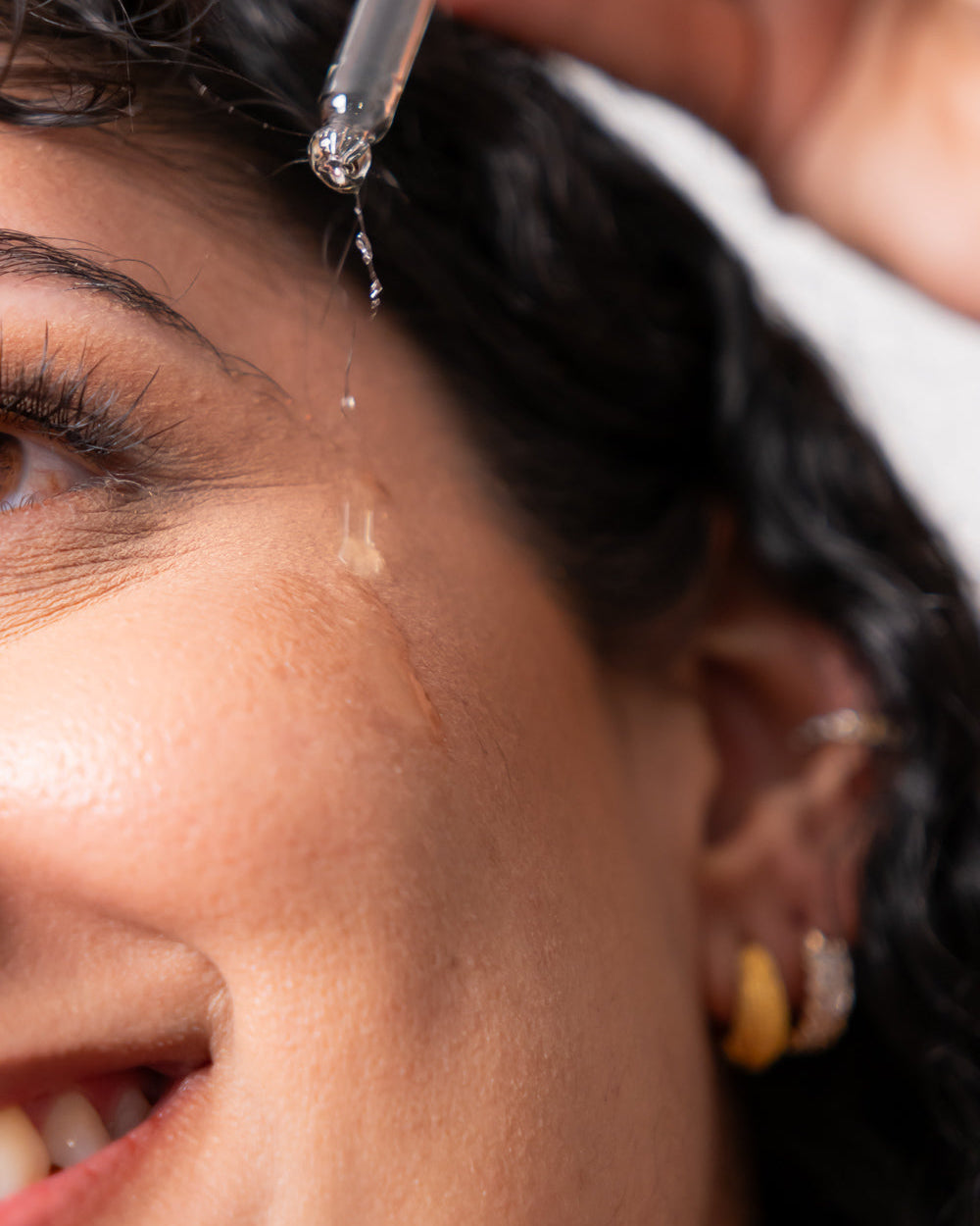 Woman dropping face oil on her cheek